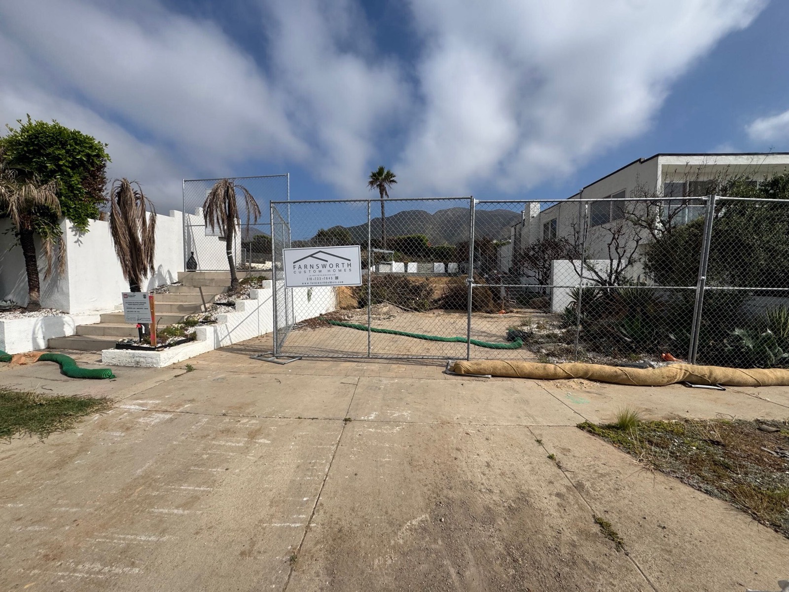 Cleared and fenced Pacific Palisades lot with Farnsworth Builders signage, secured and awaiting permits.